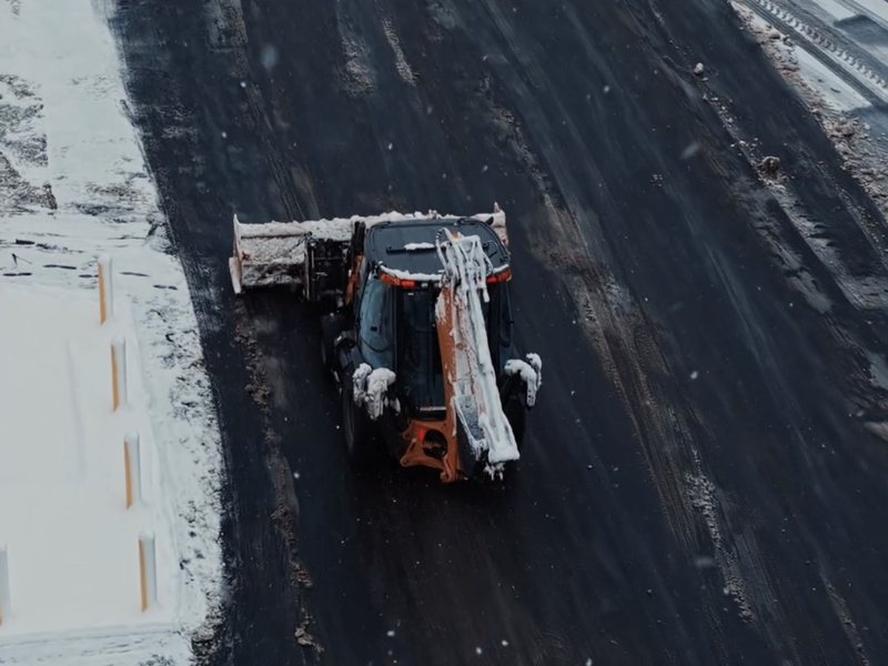 Aerial view of a commercial parking lot plowed clear to bare pavement with snow banked off to the sides