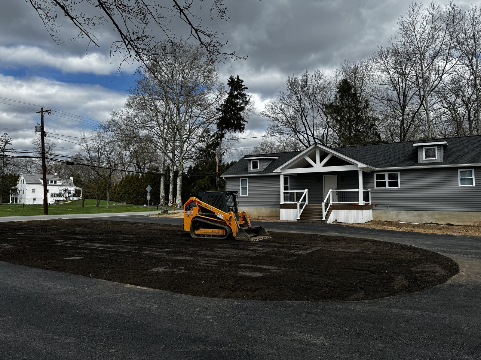 Skid steer grading a new driveway and turnaround at a renovated residential property
